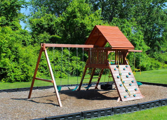 a swing set with a wooden playset in a backyard  at Four Worlds Apartments, Cincinnati, OH