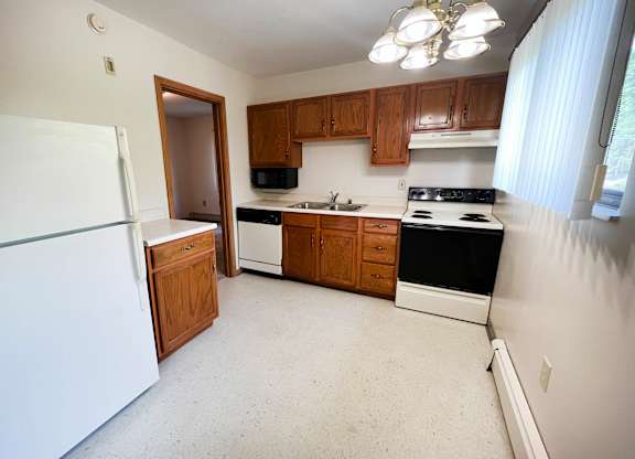 A kitchen with white appliances and wooden cabinets.