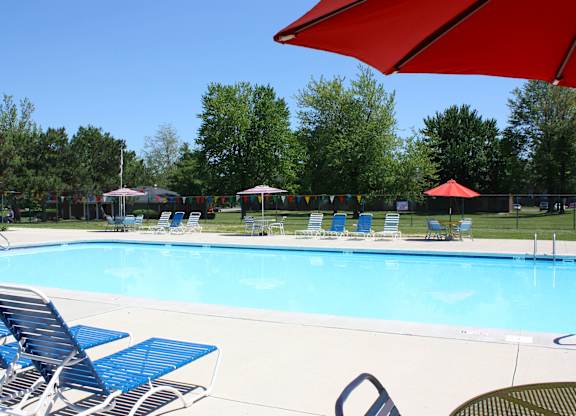 A pool with blue chairs and a red umbrella.