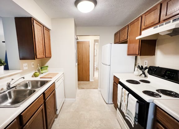 full kitchen with white appliances and wooden cabinets and a white refrigerator at The Vinings Apartments, Cincinnati