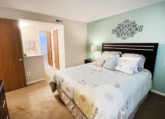a bedroom with a bed and a door to a bathroom at The Vinings Apartments, Cincinnati, 45245