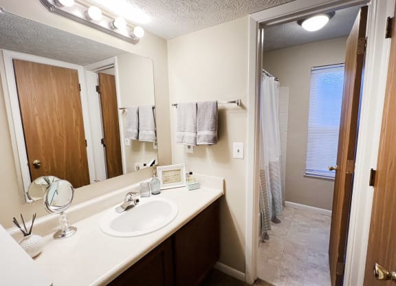 a bathroom with a sink and a mirror and a shower at The Vinings Apartments, Cincinnati, Ohio