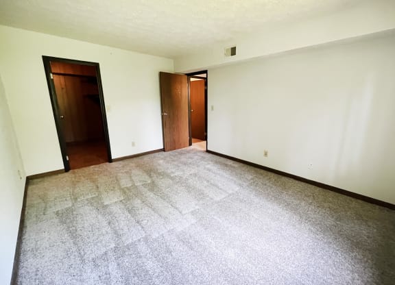 an empty living room with a carpeted floor and two doors  at Devou Village, Ft. Wright, Kentucky