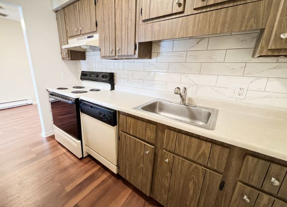 a kitchen with white appliances and wooden cabinets at Concord Woods Apartments, Milford