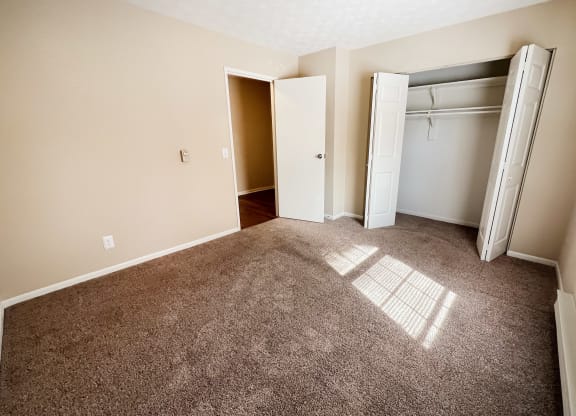 an empty room with carpet and an open closet at Concord Woods Apartments, Milford, 45150