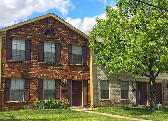 A red brick house with a tree in front.