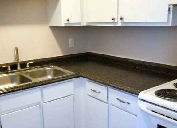 A kitchen with white cabinets and a black countertop.