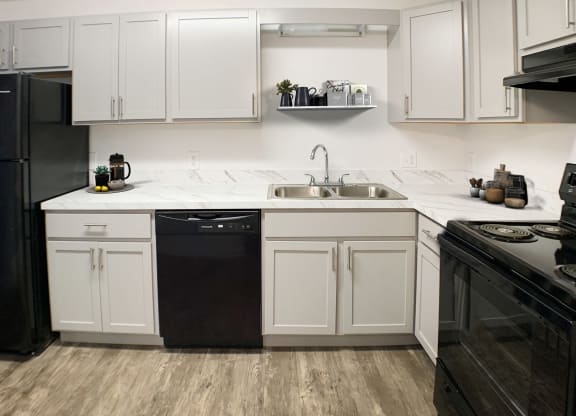 a kitchen with white cabinets and black appliances  at Knobs Pointe Apartments, New Albany, IN