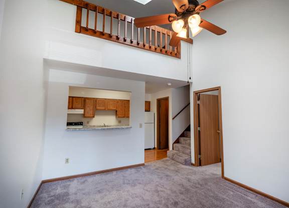 A room with a ceiling fan and a staircase.