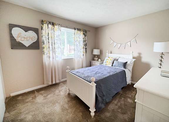 A bedroom with a white bed and a blue bedspread.