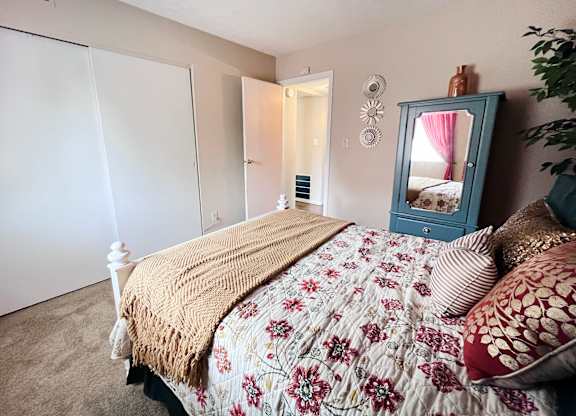 A bedroom with a bed, a mirror, and a dresser.