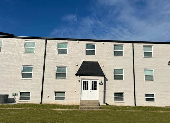 A white building with a black roof and a white door in the center.