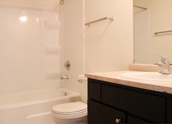 A white toilet sits next to a white bathtub in a bathroom.