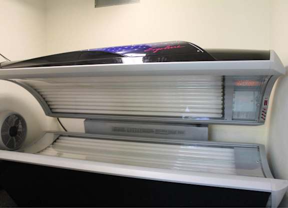 A tanning bed with a black cover and a fan on the left side.