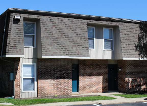 A brick building with a black door and a window with white blinds.