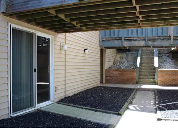A patio area with a door and steps leading to a garage.
