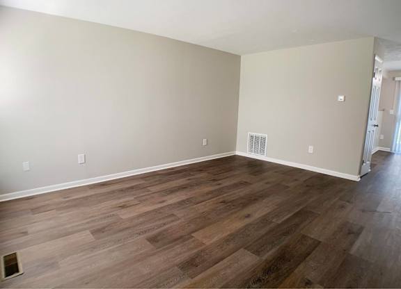 A room with wooden flooring and a window on the left side.