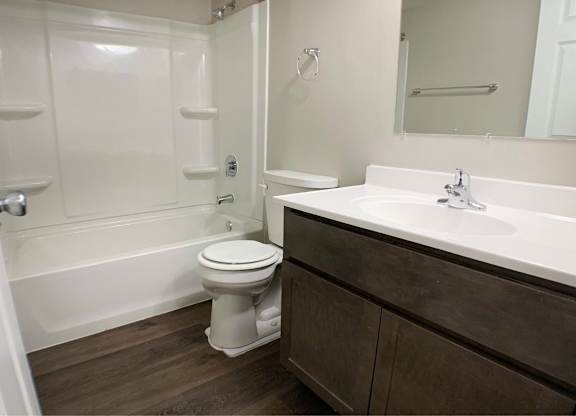 A white toilet sits in a bathroom next to a bathtub.