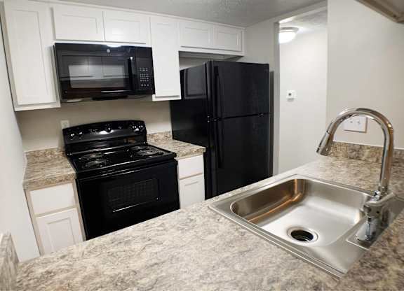 A kitchen with black appliances and a granite countertop.