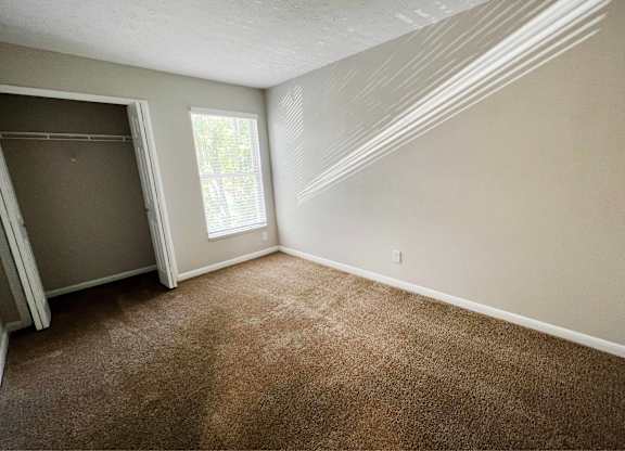 A room with brown carpet and a window.