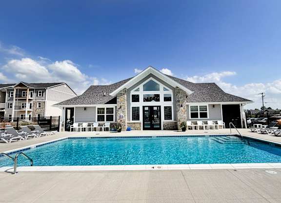 Swimming pool with clubhouse and white lounge chairs at The Meridian on 32 Apartments, Batavia, Ohio