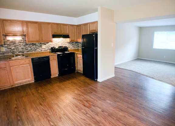 A kitchen with black appliances and wooden floors.