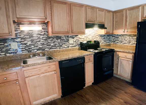 A kitchen with wooden cabinets and black appliances.