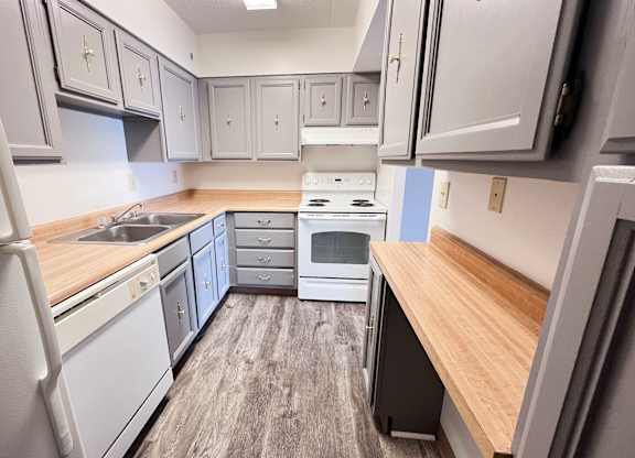 A kitchen with white appliances and wooden countertops.