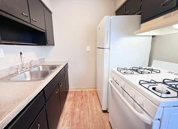 A kitchen with a white stove and black cabinets.