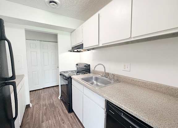 A kitchen with black appliances and white cabinets.