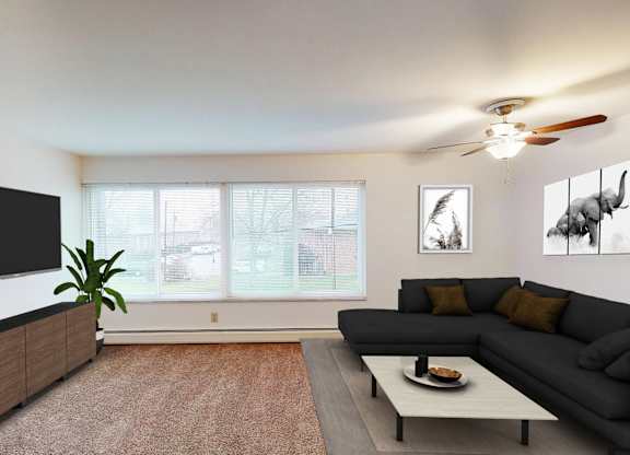 A living room with a grey couch, a black television, and a potted plant.