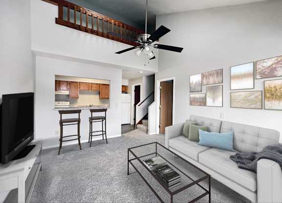 A living room with a white couch, a television, and a bar area.