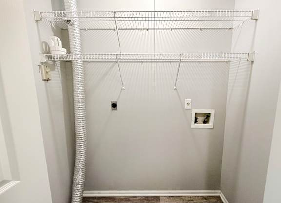 A white closet with a white pipe and a white shelf.