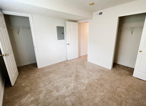 an empty bedroom with two closets and a carpeted floor  at Walton Ridge Apartments, Walton