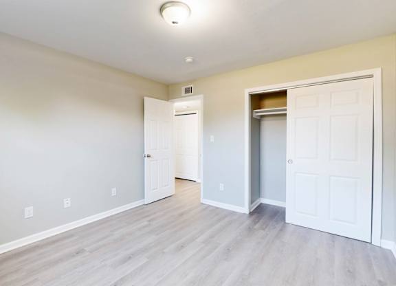an empty living room with white doors and a door to a closet