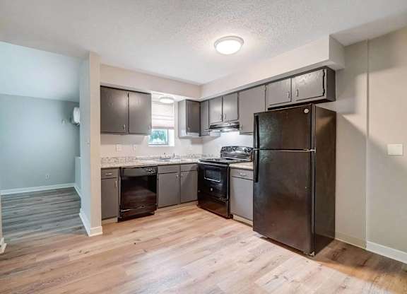 A kitchen with a refrigerator, oven, and sink.