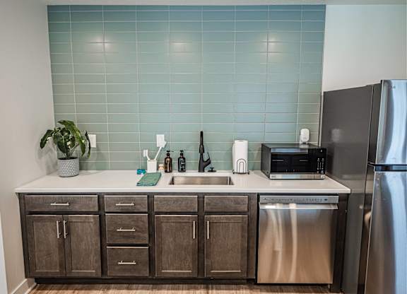 A kitchen with a stainless steel refrigerator and wooden cabinets.