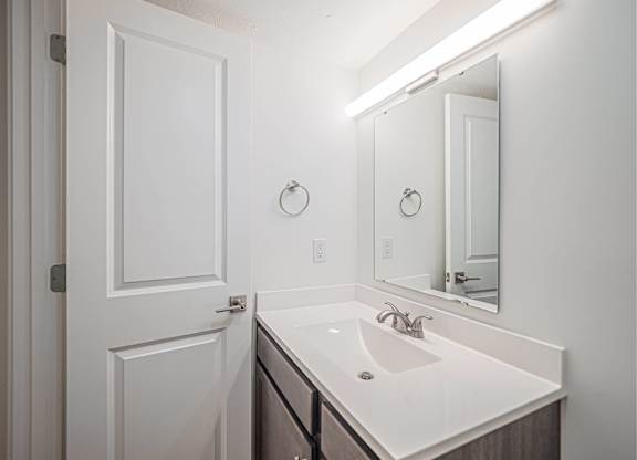 A white bathroom with a sink and mirror.
