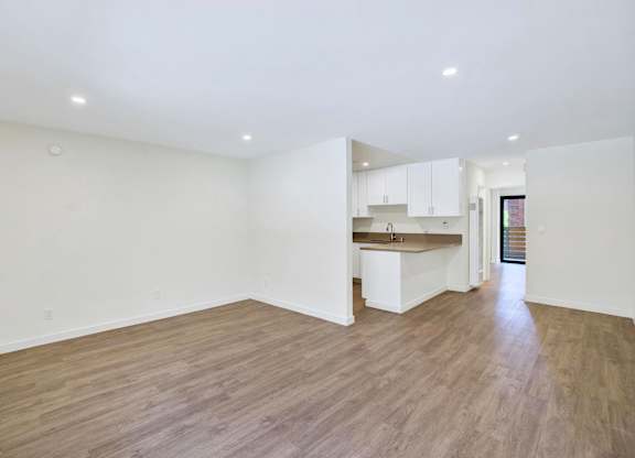 A spacious room with wooden flooring and white walls.