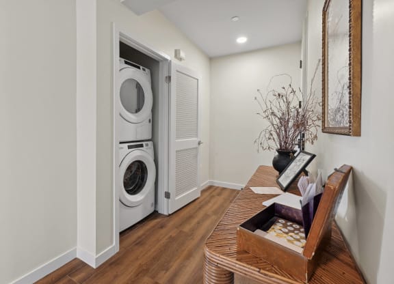 a living room with a table and a washer and dryer in a door The Baxter in Los Angeles, CA 90028