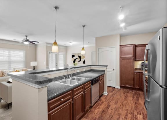 A modern gourmet kitchen with stainless steel appliances, dark espresso wood cabinetry, a pantry closet, track lighting, and a breakfast bar.