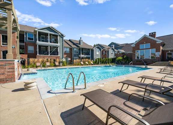 A pool surrounded by lounge chairs and buildings in the background. at Somerset Oaks Apartment Homes, Olathe, KS