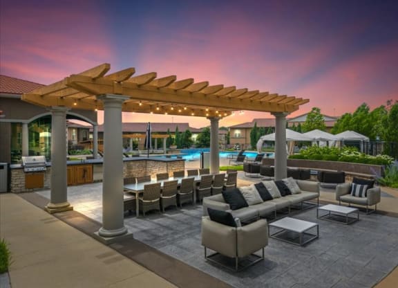a patio with couches and chairs under a wooden canopy
