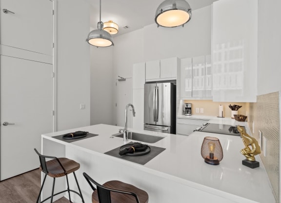 a kitchen with white cabinetry and a large white island with a sink and two stools