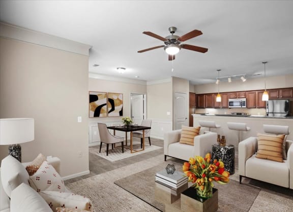 A living room with a dining area, open kitchen, crown molding and ceiling fan.