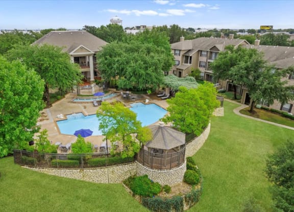 an aerial view of an apartment complex with a large pool in the middle of the yard at The Clairborne Apartment Homes, Grand Prairie