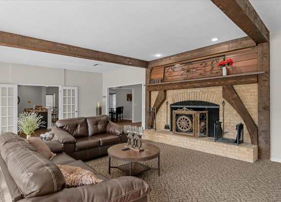 A living room with a brown leather couch and a fireplace.