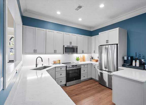 A modern kitchen with stainless steel appliances and white countertops.at The Claremont Apartment Homes, Overland Park