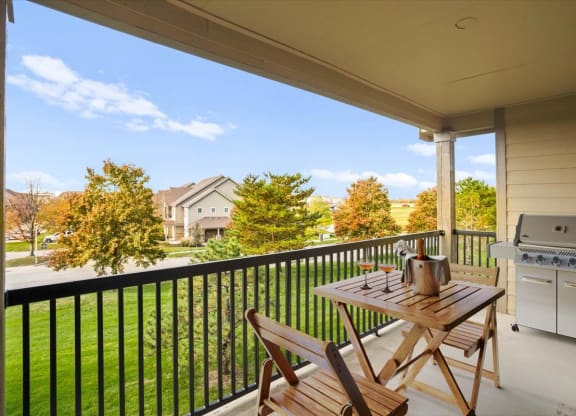 A spacious, covered private balcony overlooking a beautiful grassy area with landscaping.