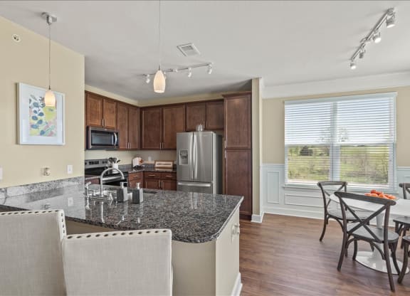 a kitchen with a granite counter top and a table with chairs at The Residences at Bluhawk, Overland Park, 66085